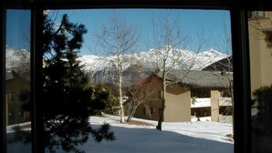 Schneebedeckte Berglandschaft mit einem Haus und einem Baum im Vordergrund.