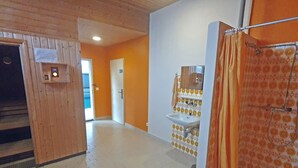 A bathroom with a shower, a sink, and a mirror. There is a wooden door and a tiled floor. - Holiday Park A06 by Interhome (St. Moritz)