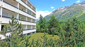 A multi-story hotel with balconies, surrounded by lush greenery and mountains in the background. - Holiday Park A06 by Interhome (St. Moritz)