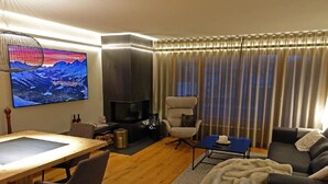 Una sala moderna con una mesa de comedor de madera, un sofá, un televisor y una chimenea.