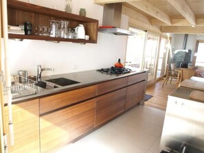 Une cuisine moderne dotée d’un plan de travail en bois, d’un évier en acier inoxydable et d’une cuisinière à gaz.
