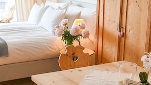 Une chambre d’hôtel avec un lit, une table de chevet en bois avec une lampe et des fleurs, et une porte en bois ornée d’un porte-clés en forme de cœur.