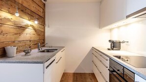 Une cuisine moderne avec un lambris en bois, un lave-vaisselle encastré et un plan de travail sur lequel se trouve une machine à café.