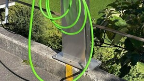 Een KEBA laadstation voor elektrische voertuigen met een groene kabel, gelegen voor een bergachtig landschap.