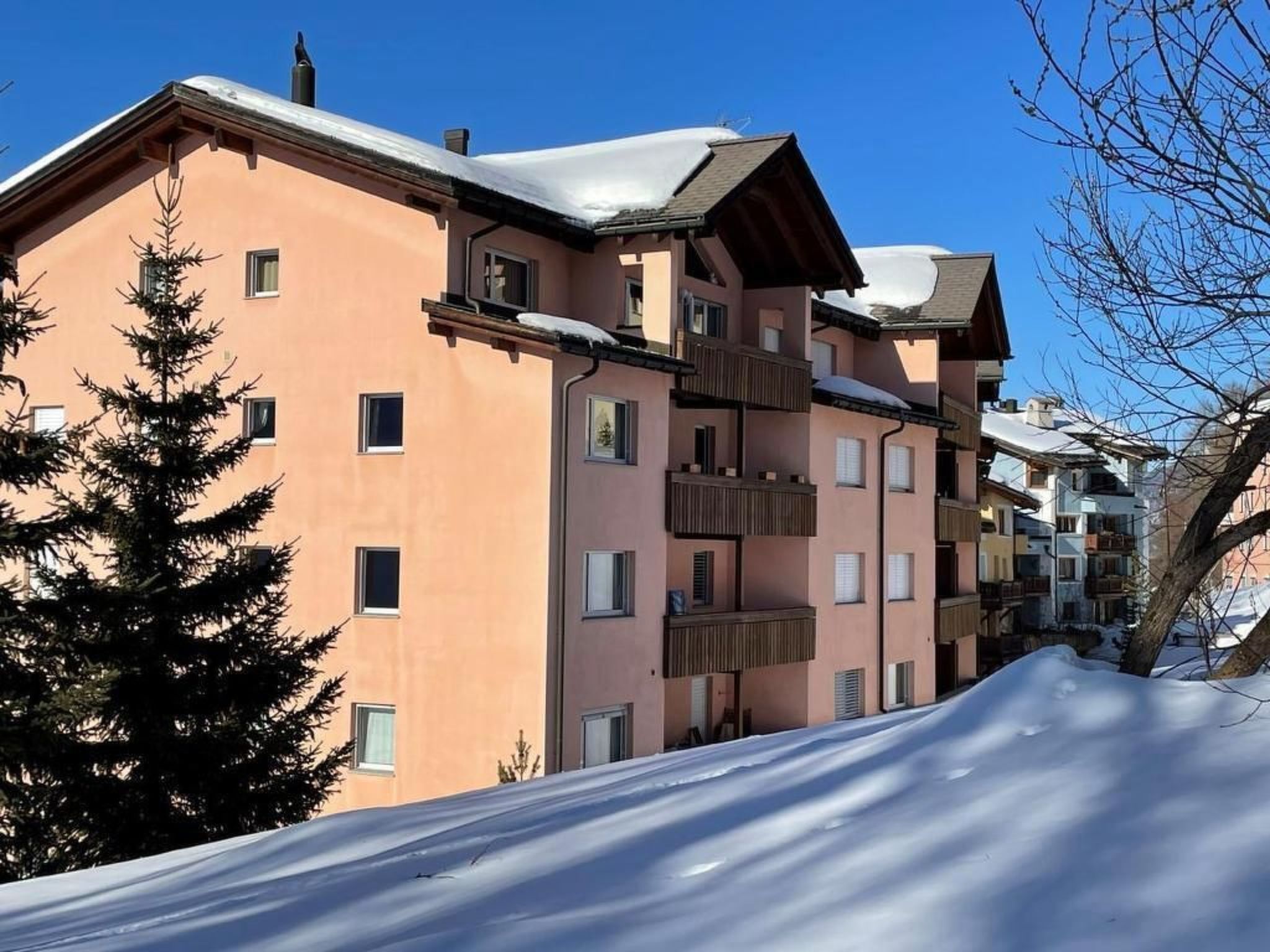 A multi-story building with balconies and a snow-covered roof.