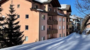 Un edificio de varios pisos con balcones y techo cubierto de nieve.
