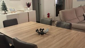 Una sala de estar moderna con una mesa de comedor de madera, un sofá y un pequeño árbol de Navidad.