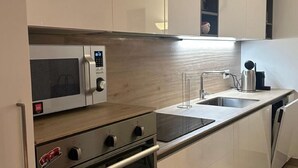Una cocina moderna con muebles blancos, microondas integrado, estufa y lavavajillas.