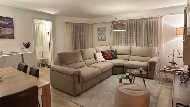 Una sala de estar moderna con un sofá seccional, una mesa de comedor y una mesa de centro.