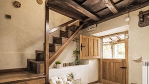 A wooden staircase leading to a room with a wooden door, a small window, and a wall-mounted light fixture.