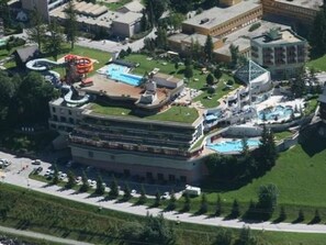 A hotel with multiple swimming pools, a water park, and a large building with a green roof. - Tschal 16 by Interhome (Leukerbad)