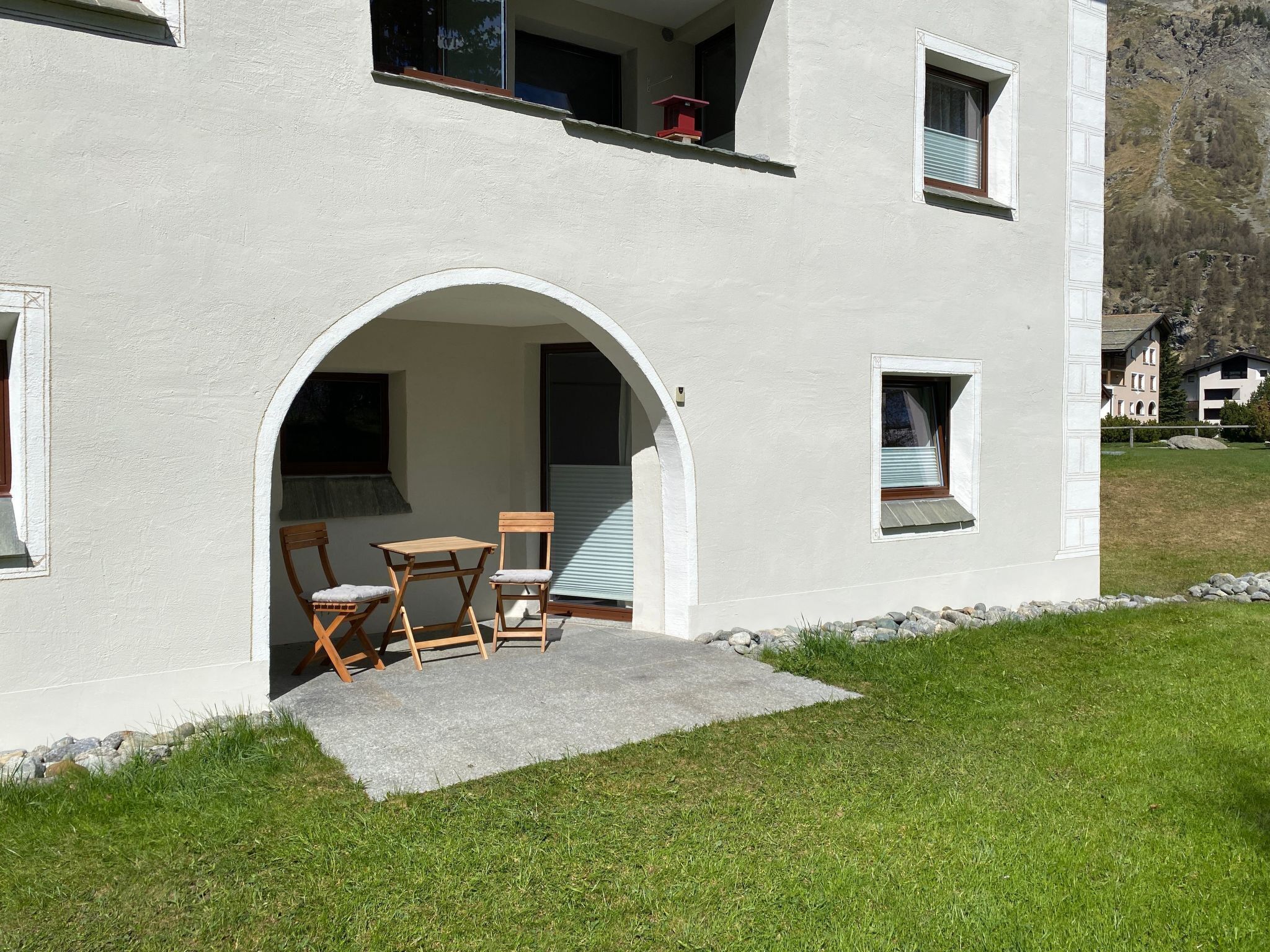 A two-story building with a small patio area featuring a table and chairs.