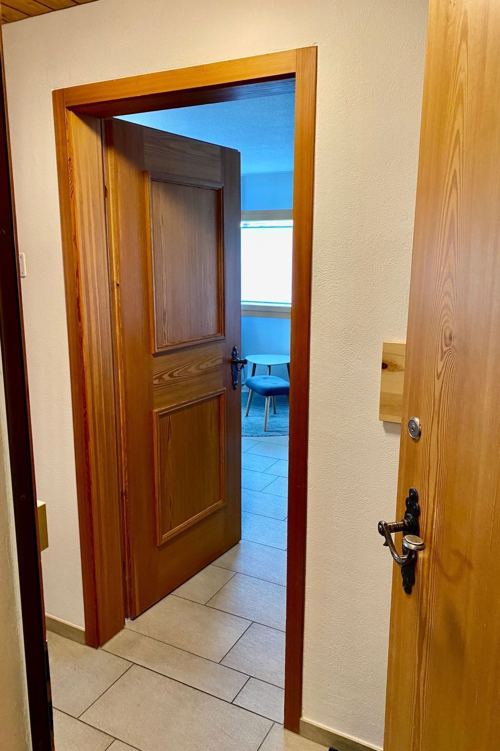 Une porte en bois donnant sur un petit patio aménagé avec une table et une chaise.