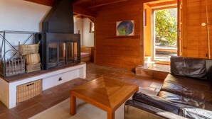 Interior acogedor de una cabaña con chimenea, paredes de madera, un sofá y piso de baldosas.