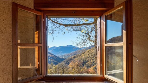 Una habitación con un ventanal que ofrece vistas a un paisaje montañoso.