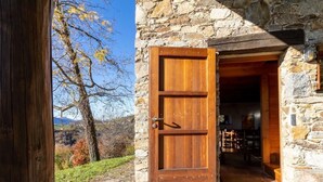 Un edificio de piedra con una puerta de madera abierta a una habitación con chimenea y vistas al exterior.