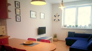 Un espacio habitable compacto con comedor, sofá, televisor y ventana con vistas.