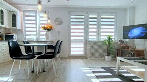 Una cocina moderna con armarios blancos, una mesa de comedor con sillas negras, un microondas y un reloj en la pared.