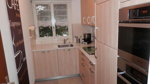 A compact kitchen with light wood cabinets, a stainless steel sink, and a built-in oven. - Al Bosco 71A by Interhome (Lugano)