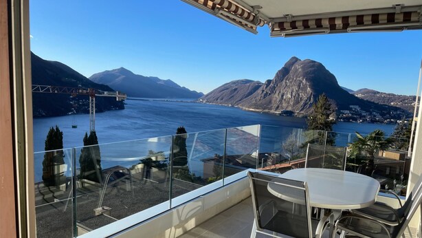 Ein Balkon mit Glastrennwand, einem Tisch und einem Stuhl.