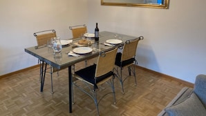 Ein Essbereich mit einem Glastisch, Korbstühlen und einem Spiegel darüber.