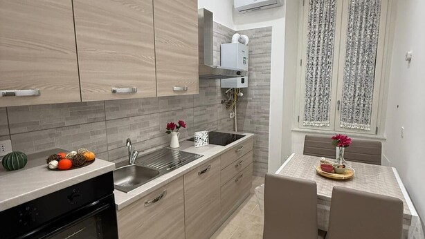 Una cocina moderna con armarios de madera, horno empotrado y una zona de comedor con mesa y sillas.
