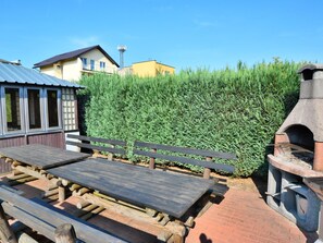 Un patio con bancos de madera y una parrilla de piedra.