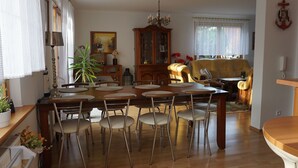 Een eetgedeelte met een houten tafel en stoelen, een kroonluchter en een kast met glazen deuren.