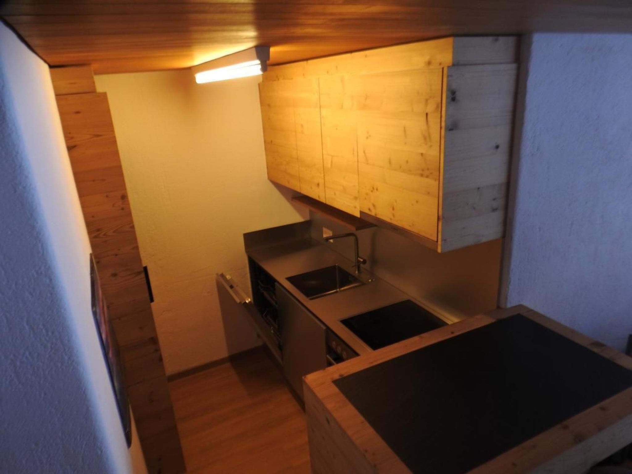 A compact kitchen with wooden cabinets, a countertop, and a sink.