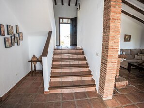 Eine Treppe führt zu einem Raum mit einer Ziegelstütze, einem Sofa und einer Wand mit gerahmten Bildern.