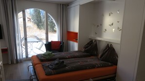 Habitació compacta amb un llit, una cadira i vista a l'exterior a través d'una finestra gran.