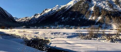 A snow-covered landscape with mountains, a river, and a small settlement.