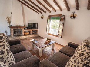 A living room with a fireplace, a television, a window with a view, and a sofa. - Cantoblanco Häuser 2 by Interhome (Los Romanes)