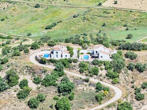 A two-story house with a swimming pool, surrounded by greenery and a winding road. - Cantoblanco Häuser 2 by Interhome (Los Romanes)