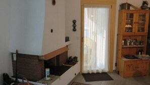 Ein Wohnzimmer mit Kamin, einer Holzkabine mit Glastüren und einer Tür mit weißem Vorhang.