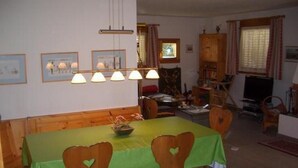 Ein Essbereich mit einem grünen Tisch, Holzstühlen, einer Kandelaber und gerahmten Bildern an der Wand.
