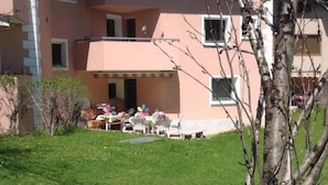 Ein Gebäude mit Flachdach, überdachter Terrasse und Sitzgelegenheiten sowie einem Rasen.