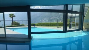 A swimming pool with a view of mountains and a person walking by. - Palazzo Ascolago Nr. 27 by Interhome (Ascona)