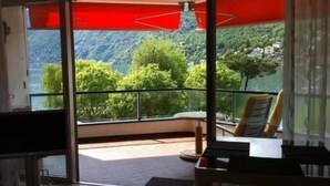 A room with a large sliding glass door leading to a balcony with a mountain view. - Palazzo Ascolago Nr. 27 by Interhome (Ascona)