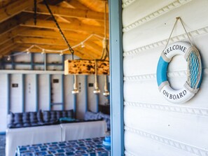 A room with a bed, a table, and a wall-mounted life preserver sign. - for 5 people by Interhome (Rusinowo)