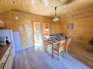 A wooden cabin interior with a kitchen, dining area, and a door leading outside. - with swimming pool by Interhome (Rusinowo)