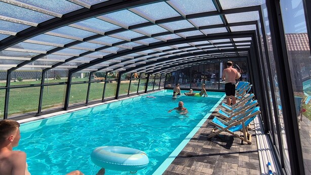 Una piscina interior con paredes de vidrio transparente, suelo de baldosas y techo cubierto.