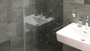 A modern bathroom with a glass-enclosed shower, a white sink, and a large mirror. - Casa Torri by Interhome (St. Moritz)