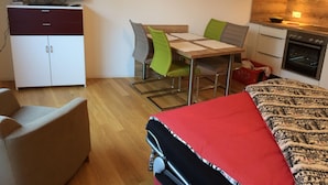 A compact hotel room with a bed, a desk with chairs, a television, a wardrobe, and a kitchenette. - Casa Torri by Interhome (St. Moritz)