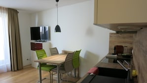 A compact kitchen with a dining area, a flat-screen TV, and a small kitchenette. - Casa Torri by Interhome (St. Moritz)