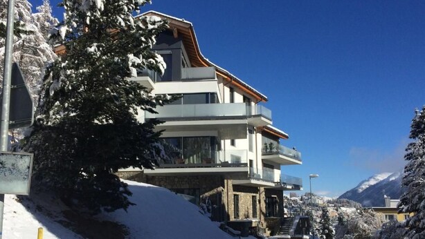 A modern multi-story building with balconies, situated in a snowy landscape with mountains in the background. - Casa Torri by Interhome (St. Moritz)
