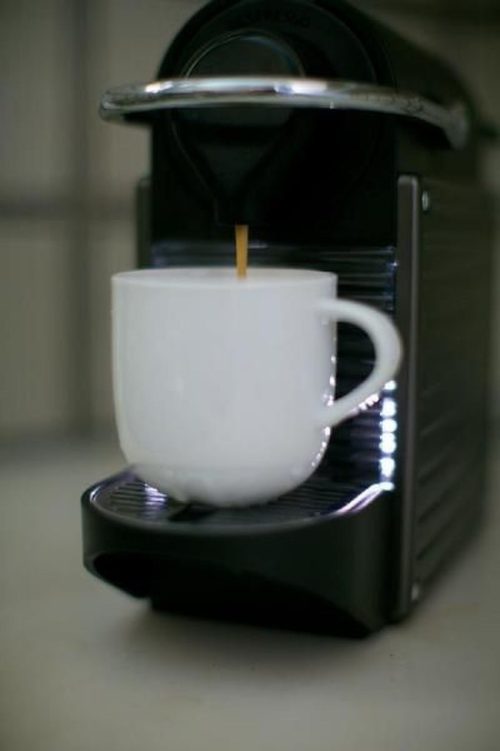 En kaffemaskin med en vit kopp placerad under utloppet.