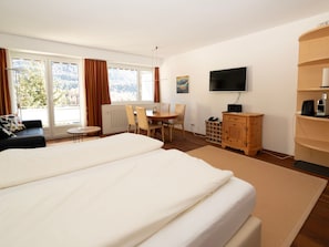 Une chambre d’hôtel avec un grand lit, un bureau, une chaise, une télévision et une vue sur l’extérieur.