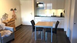Une cuisine moderne avec des meubles blancs, une table à manger en bois et des chaises noires.