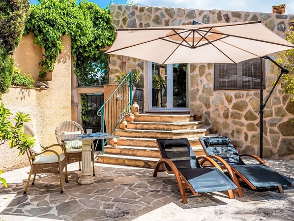 A stone staircase leading to a door, wicker chairs, a table with a cup, and a large umbrella. - Juniorsuite by Interhome (Son Gall Vell)